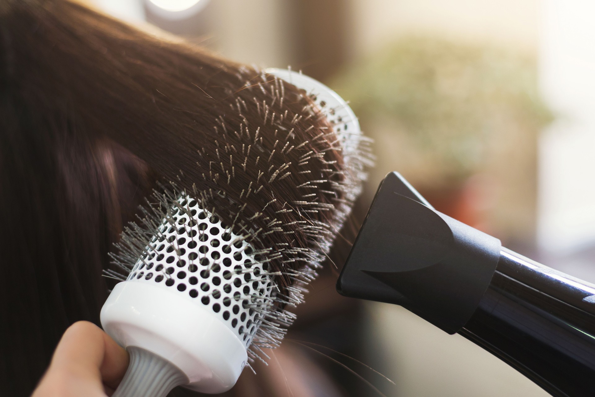 Hairdresser drying woman's hair in beauty salon